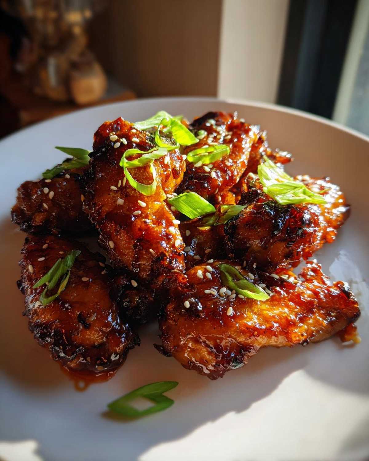 Close-up of glossy, glazed Honey Soy Chicken Wings Crispy Oven Baked, garnished with sesame seeds and green onions.