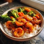 A close-up of a serving of Honey Soy Shrimp Bowl with Rice, featuring glazed shrimp, steamed broccoli, and carrots over white rice.