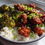 Close-up of a Honey Sriracha Chicken Bowl featuring glazed chicken pieces over white rice and charred broccoli florets.