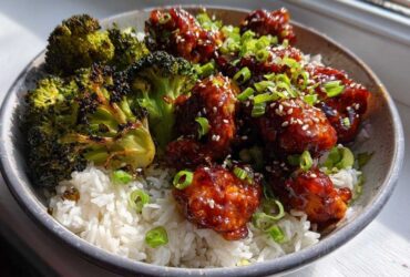 Close-up of a Honey Sriracha Chicken Bowl featuring glazed chicken pieces over white rice and charred broccoli florets.