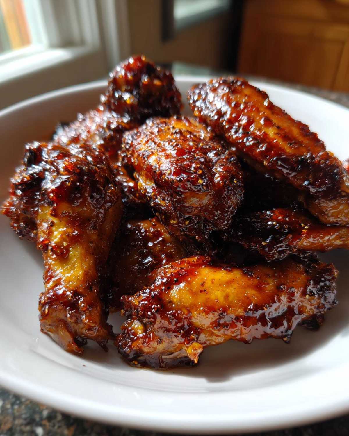 Close-up of glistening, sticky Honey Garlic Chicken Wings Oven Baked piled in a white bowl.