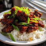 Close-up of Sticky Sweet Chili Chicken Skillet pieces coated in dark glaze, served over white rice and topped with fresh green onions.