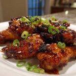 Close-up of glistening Sticky Teriyaki Chicken Wings Oven Baked, garnished with sesame seeds and sliced green onions.