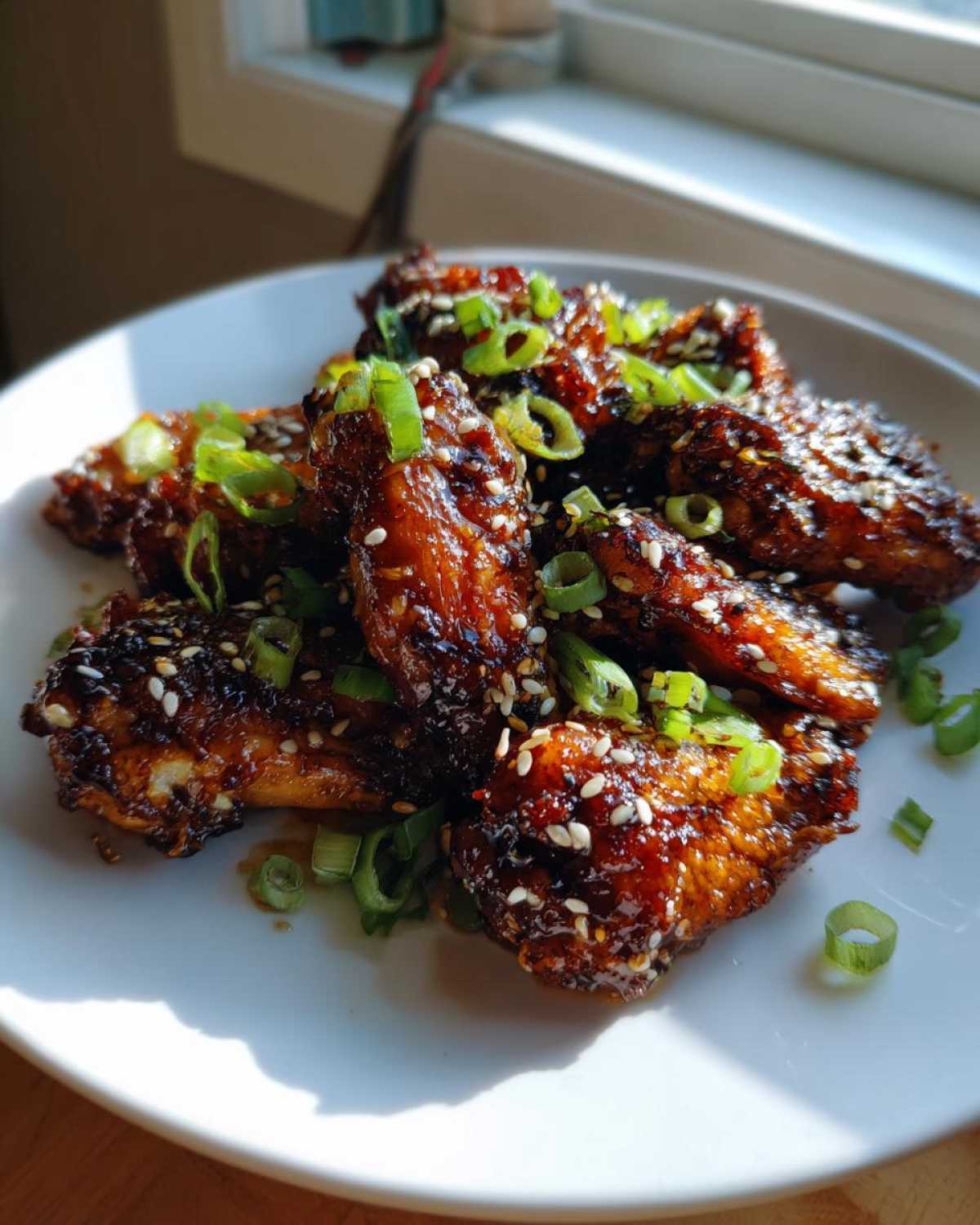 Close-up of glossy Sticky Teriyaki Chicken Wings Oven Baked, garnished with sesame seeds and green onions.