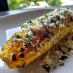 Close-up of perfectly cooked Air Fryer Corn on the Cob topped with crumbled white cheese and fresh parsley.