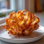 A perfectly cooked Air Fryer Crispy Mini Blooming Onion Golden Fun, golden brown and crispy, served on a white plate.