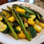 Close-up of sautéed Asparagus with Zucchini and Squash pieces seasoned on a white plate.