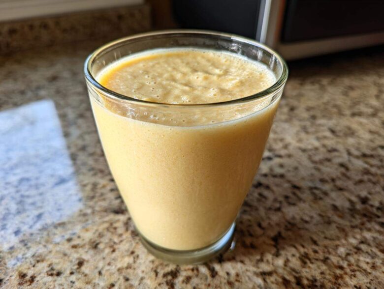 A close-up of a thick, creamy Banana Chamomile Tea Smoothie served in a clear glass on a granite countertop.