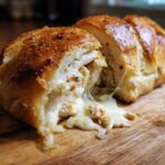 Close-up of Cheesy Garlic Chicken Rolls cut open, showing shredded chicken and gooey melted cheese stretching out.