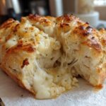 Close-up of a golden-brown Cheesy Garlic Chicken Rolls loaf pulled apart, showing melted, stretchy cheese inside.