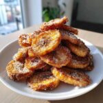 A tempting pile of golden brown Cinnamon Sugar Banana Chips generously coated in sparkling sugar, served on a white plate.