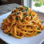 A generous serving of creamy cajun chicken pasta tossed with shredded chicken and topped with fresh parsley.
