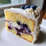 Close-up of a slice of Fluffy Lemon Blueberry Naked Cake Homemade with Whipped Cream Frosting.