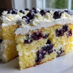 Close-up of two slices of Fluffy Lemon Blueberry Naked Cake Homemade with Whipped Cream Frosting, showing moist yellow cake layers and fresh blueberries.