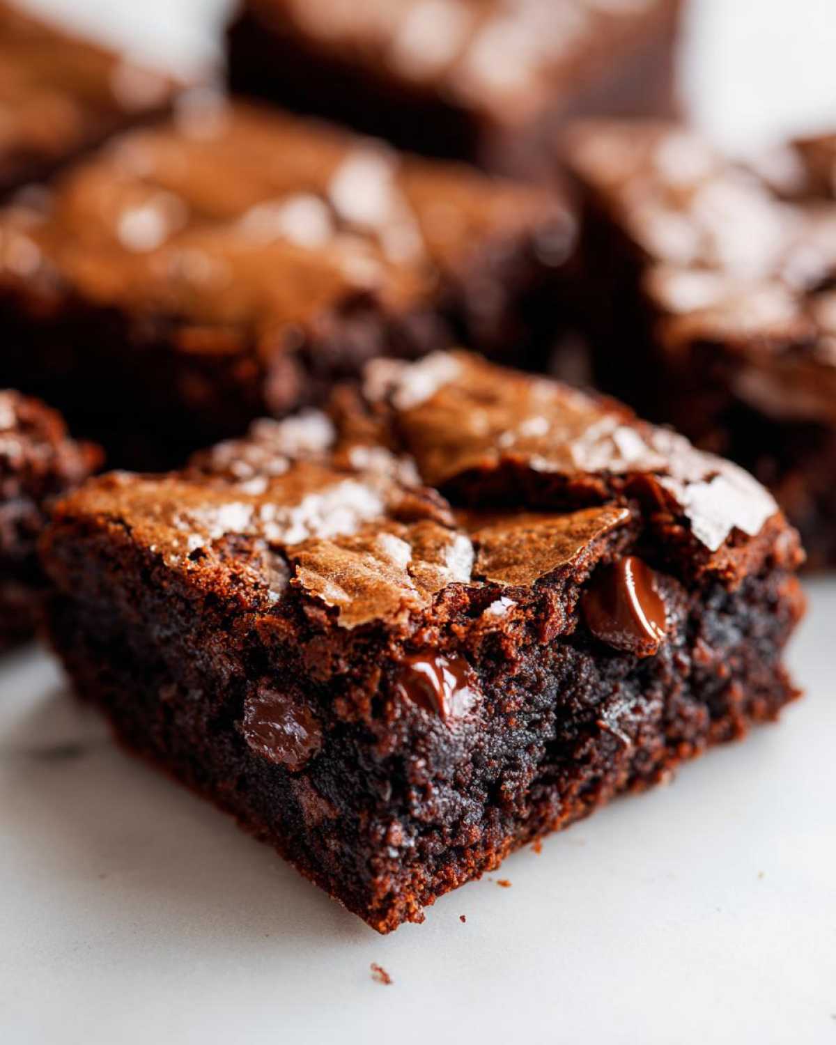 A close-up, rich, fudgy square of Brookies showing melted chocolate chips and a flaky sea salt topping.