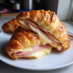Close-up of Golden Baked Ham and Cheese Croissants, cut in half showing melted cheese and ham layers.