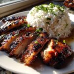 Slices of glazed Hawaiian Chicken served next to a mound of white coconut rice topped with fresh herbs.