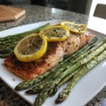 A perfectly cooked salmon fillet served with roasted asparagus and topped with lemon slices, ideal for High Protein Meals That Melt Belly Fat Fast Without Dieting.