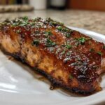 A perfectly cooked fillet of Honey Garlic Glazed Salmon, glistening with a rich brown sauce and topped with fresh parsley.