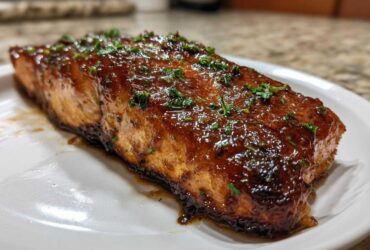 A perfectly cooked fillet of Honey Garlic Glazed Salmon, glistening with a rich brown sauce and topped with fresh parsley.