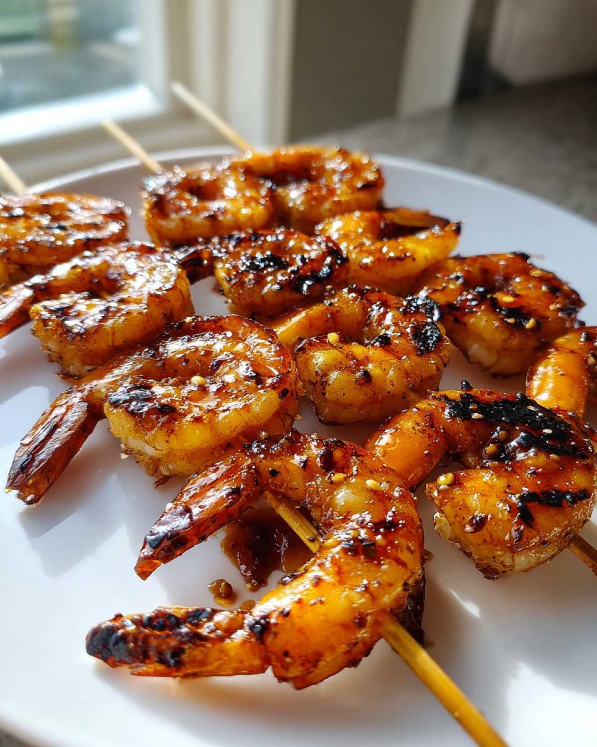 Close-up of perfectly grilled Honey Garlic Grilled Shrimp skewers glistening with glaze on a white plate.