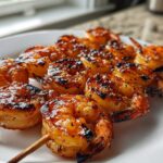 Close-up of perfectly grilled Honey Garlic Grilled Shrimp skewers glistening with glaze on a white plate.