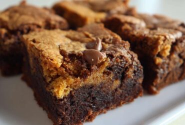 A close-up of a perfectly layered square of Brookies, showing a dense chocolate brownie base topped with a lighter cookie layer and a melted chocolate chip.