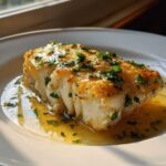 A perfectly cooked piece of Lemon Garlic Butter Cod resting in its buttery sauce, topped with fresh parsley.