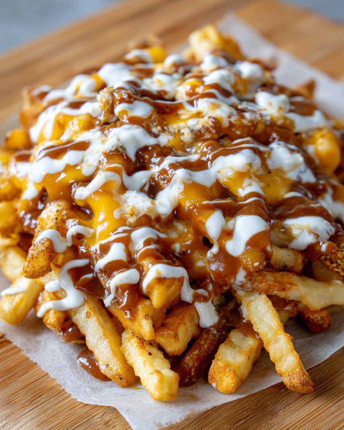 A close-up of crispy french fries loaded with melted cheese, brown gravy, and white sauce, resembling Louisiana Voodoo Fries.