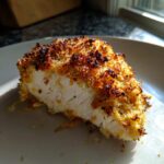 A cross-section of juicy Parmesan Baked Caesar Chicken showing the white interior and crispy, golden-brown topping.