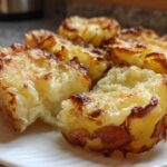 Close-up of several golden brown Parmesan Crusted Smashed Potatoes served on a white plate.