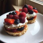 Two stacks of Protein Pancake Bowls with Yogurt and Berries, topped with fresh raspberries, blueberries, and sliced strawberries.