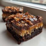 A decadent square of Samoa Box Mix Brownies showing layers of chocolate, caramel, and toasted coconut topping.