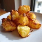 A pile of golden brown, crispy Simple Irish Roasted Potatoes served on a white plate.