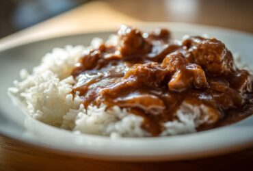 Close-up of tender chicken pieces covered in rich brown gravy served over fluffy white rice, perfect for Smothered Chicken and Rice.