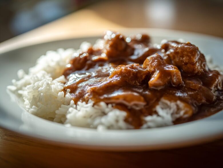 Close-up of tender chicken pieces covered in rich brown gravy served over fluffy white rice, perfect for Smothered Chicken and Rice.