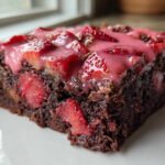 Close-up of a rich, fudgy Strawberry Brownies with Sweet Strawberry Glaze slice topped with fresh strawberries.