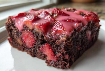 Close-up of a rich, fudgy Strawberry Brownies with Sweet Strawberry Glaze slice topped with fresh strawberries.