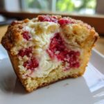 Close-up of a Strawberry Cream Cheese Muffins cut in half showing the fluffy cake, bright red strawberries, and creamy filling.