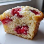 Close-up of a halved Strawberry Cream Cheese Muffin showing the moist crumb and bright red strawberry filling.