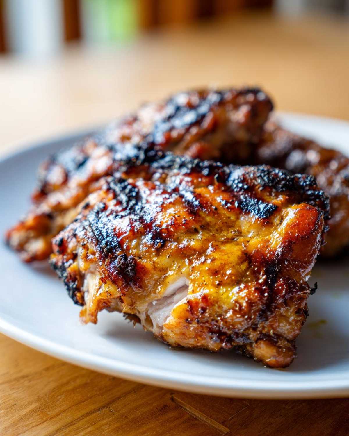 Close-up of perfectly charred and glazed Vietnamese Grilled Chicken pieces resting on a white plate.