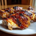 Close-up of two pieces of glistening, caramelized Vietnamese Grilled Chicken served on a white plate.