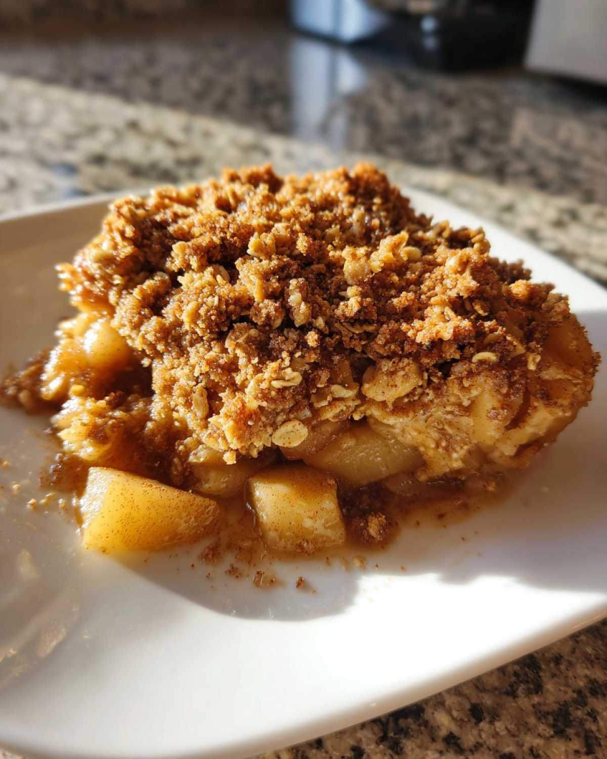 A close-up serving of warm Apple Crisp featuring tender spiced apples beneath a thick, golden-brown oat crumble topping.
