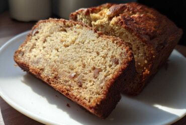 Two thick slices of moist Apple Cinnamon Bread showing visible chunks of apple and a golden-brown crust, served on a white plate.