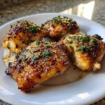 Four glistening, grilled chicken thighs coated in garlic parmesan glaze and topped with fresh parsley.