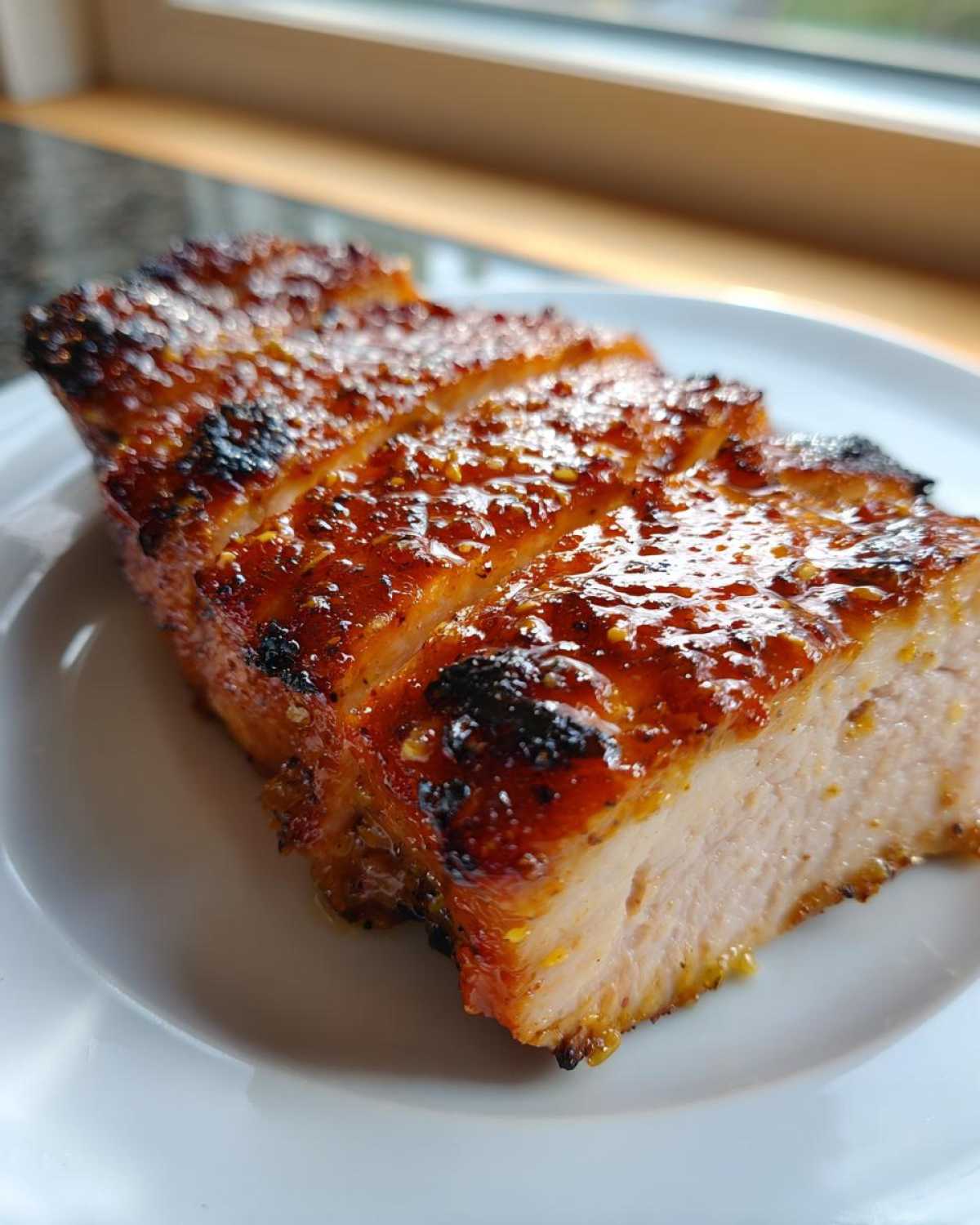 Close-up of a thick, juicy piece of Grilled Honey Mustard Chicken Breasts, sliced and glazed.