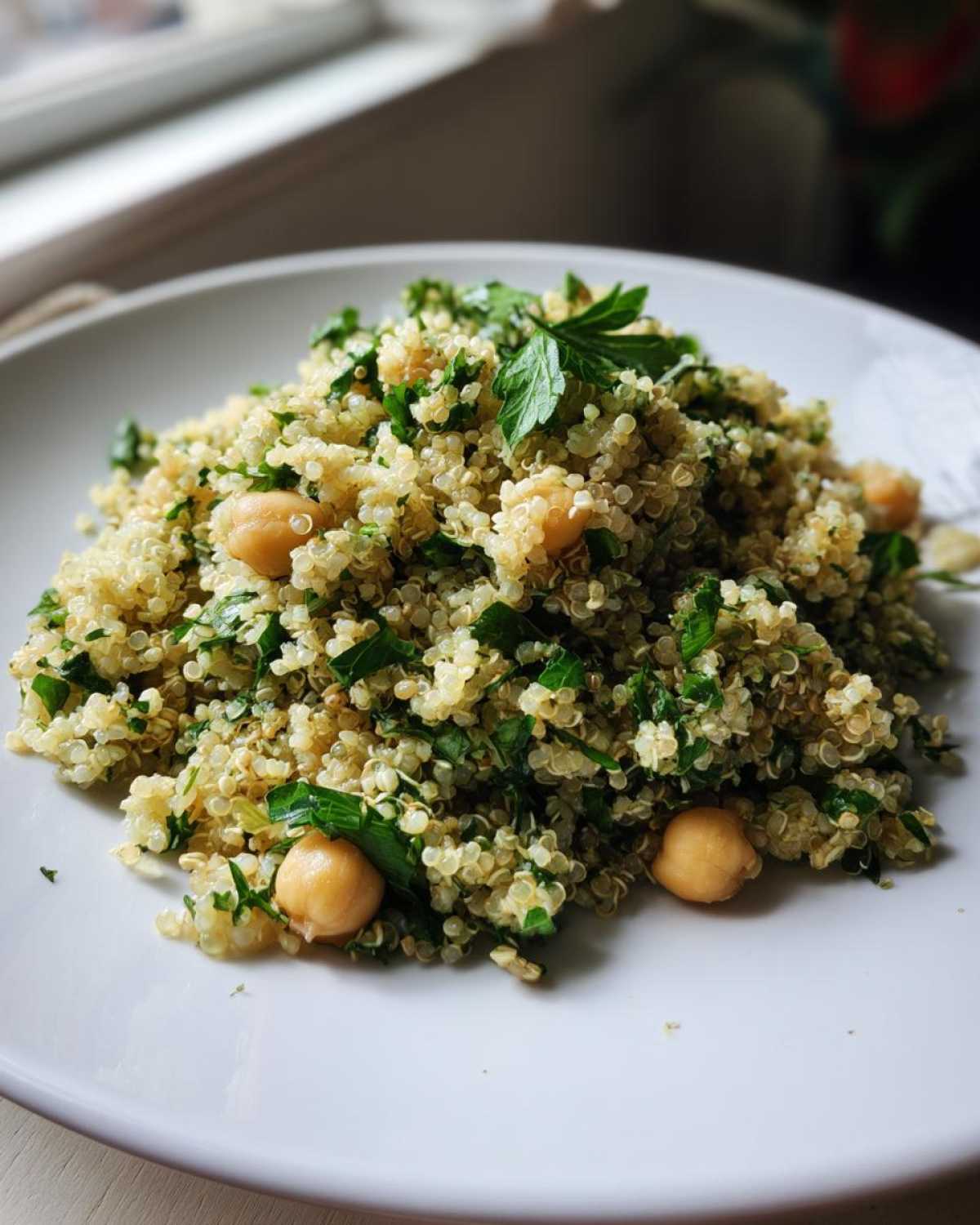 Close-up of a serving of quinoa mixed with chickpeas and fresh parsley, resembling the Jennifer Aniston Salad.