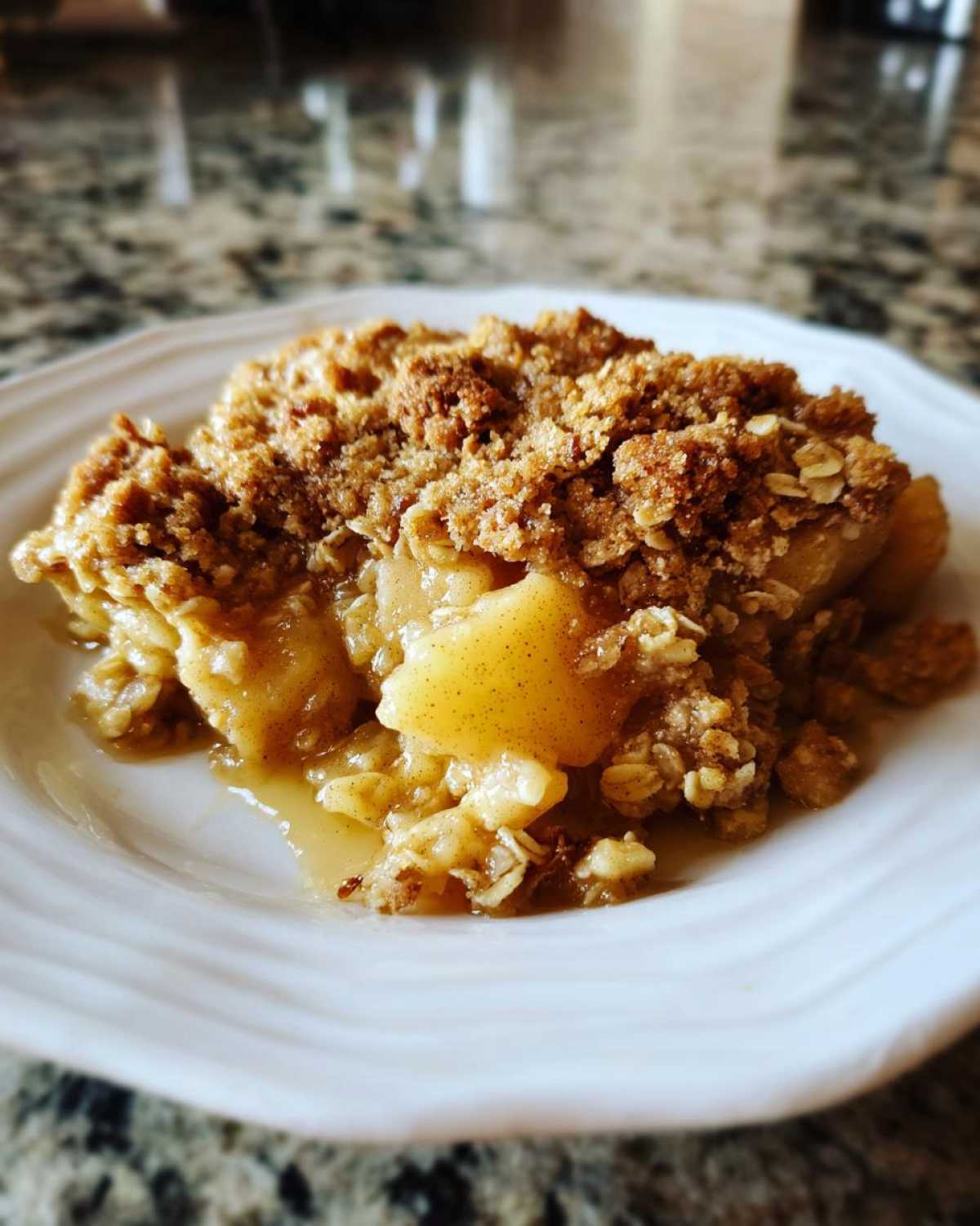 A close-up serving of warm Apple Crisp showing soft baked apples and a thick, crunchy oat crumble topping.