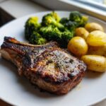 A perfectly cooked Sheet Pan Lemon Garlic Pork Chop served with roasted potatoes and steamed broccoli.