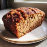 A close-up slice of moist Snickerdoodle Banana Bread showing a rich, brown, sugary top crust.